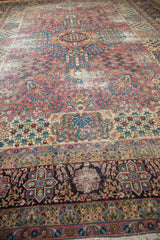 Antique Kerman carpet's dark main border with dense floral patterns and pile wear.