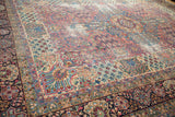Antique Kerman carpet's spiraling pinwheel floral design in cochineal red, sky blue, and ivory.