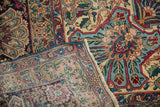 Folded edge of antique Kerman carpet, showing intricate floral patterns, meandering vines, and evident pile wear.