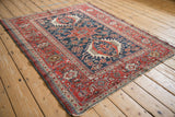 Angled perspective of an antique Karaja rug highlighting its traditional triple medallion in red and cobalt blue.