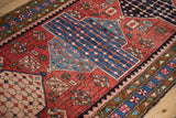 Angled detail of a Baktiari rug's blue seed design, red field, and patterned borders.