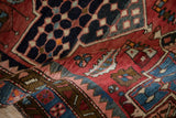 A fold in the Baktiari rug reveals the short pile over its brick red field and interconnected seed design.