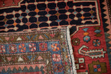 Close view of a Persian Baktiari corner with checkered floral borders and a dark navy seed-pattern field.