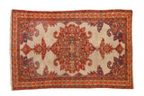 Antique fine Malayer rug with a central roundel medallion in red, orange, and blue on an open ivory field.