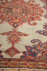 Angled view showing the low, textured pile and scrolled finials of an antique Malayer rug.