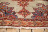 Antique Malayer rug corner with scrolled spandrels, a floral border, and visible low pile texture.