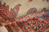 Folded corner of an antique Persian Malayer rug reveals its worn pile and detailed floral border.