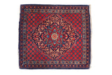 Vintage Kashan rug with a scalloped navy medallion, featuring scrolled leaves on a brick red background.