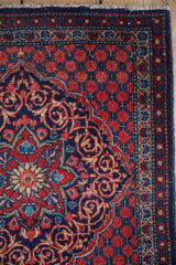 Corner detail of a Persian Kashan rug with navy arabesques and intricate floral borders.