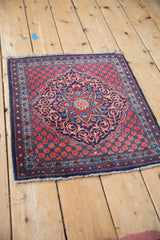 Angled perspective of a vintage Kashan rug showing its navy and brick red scalloped medallion.
