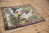 Intricate detail of dusty blush rose flowers and green foliage on the antique Kerman pictorial rug.