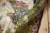 Curled antique Kerman mat: ivory figures, blush roses, green foliage, and ornate cochineal border.