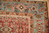 Antique Heriz rug corner showing the geometric border against the cherry red Herati-design field.