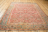 Angled view of an antique Heriz rug, showing the dense Herati pattern and its contrasting geometric border.