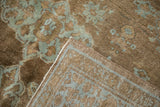 Distressed pile of an Antique Mahal carpet, muted blue floral design, and folded edge.