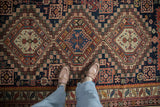 Overhead view of an antique Caucasian rug's geometric field, showing triple medallions and stylized animals.