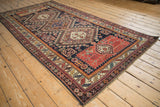 Angled perspective of an antique Caucasian runner, detailing the sequence of medallions and serrated leaf border.