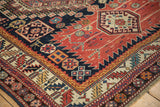 Corner detail of a Caucasian rug showing the meandering serrated leaf border and intricate geometric motifs.