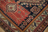 Close-up on the sprawling serrated guls and geometric borders of an antique Caucasian rug.