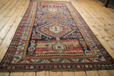 Angled perspective of an antique Caucasian runner showing its full length and triple medallion pattern.