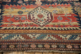 Angled view of the geometric medallion and serrated leaf borders on an antique Caucasian rug.