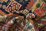 Hand-knotted pile and serrated geometric motifs on a folded antique Caucasian rug runner.
