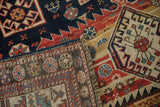 A folded corner on an antique Caucasian rug reveals its hand-knotted pile and woven foundation.