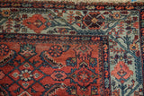 Malayer rug detail: vivid powder blue border with geometric vines meeting worn red Herati field.
