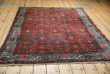 Vintage Malayer rug corner, highlighting powder blue geometric border, brick red Herati pattern field, and fringe.