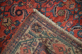 Folded Vintage Malayer rug corner, red Herati field, beige floral vine border, and fringe.