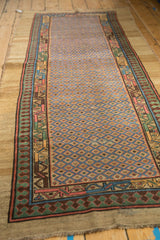 Angled view of an antique Serab runner showing its full length, lattice field, and colorful pawn motif borders.