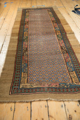 Long perspective of an antique Serab runner showing its geometric lattice field and wide camel border.