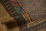 Angled view of an antique Serab's pawn design motif, camel border, and blue lattice field.