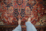 Richly colored geometric medallion and patterns of a vintage Heriz carpet seen underfoot.
