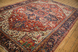 Angled perspective of a vintage Heriz carpet showing its grand-scale geometric medallion on a cherry red field.