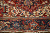 Angled detail of a vintage Heriz carpet's navy Turtle Samovar border and low, textured pile.