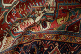 Folded vintage Heriz carpet showing rich hand-knotted texture in red, blue, and ivory hues.