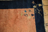 Close-up of an antique Peking rug's corner showing restored side cord and delicate floral vines.