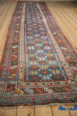 A long perspective of an antique Persian runner, showing the repeating geometric field and detailed borders.
