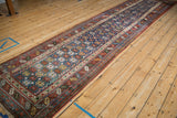 Antique Persian runner shown at an angle, highlighting its long geometric pattern and scale.