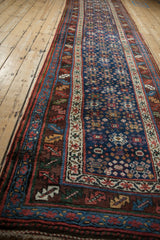 View down the length of a navy blue antique Persian runner, highlighting its intricate border designs.