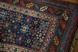 Corner detail of an antique Persian runner's intricate serrated leaf and vine borders.