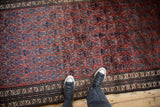 Close view of a vintage Kurd rug's short pile and staggered floral pattern in burgundy and blue.