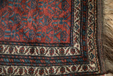 Corner view of a vintage Kurd rug showing the meandering vine border, short pile, and original fringe.