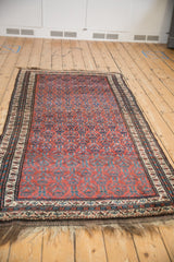 Vintage Kurd rug viewed lengthwise, featuring a dynamic pattern of staggered blue florals on a burgundy field.