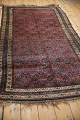 Angled view of a vintage Kurd rug showing its dynamic blue abrashes on a burgundy field.
