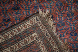 Vintage Kurd rug corner folded back showing the hand-knotted foundation and ivory fringe.