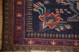 Hand-knotted vintage Afshar rug corner, madder red geometric border, deep navy field.