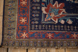 Corner of Afshar rug showing olive green, red geometric borders, and frayed end.