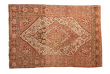 Antique distressed Farahan Sarouk rug with a central shield medallion in dusty rose, ivory, and brown.